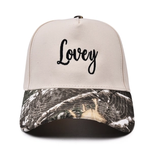Detailed close-up of beige five-panel cap with Lovey embroidery and camouflage brim