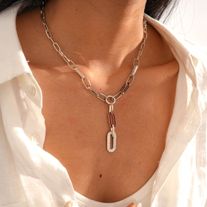 Macro shot of a silver oval pendant with inset rhinestones on a paperclip chain necklace