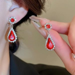 Detailed view of red teardrop earrings with sparkling crystals in flower design