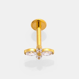 Close-up of golden G23 titanium labret stud with zircon flower design on gray background