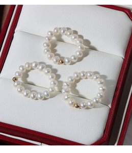 Close-up of three woven freshwater pearl rings with 14K gold bead in a red jewelry box