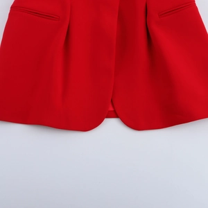 Detailed close-up of the red vest hem and pocket stitching with premium texture
