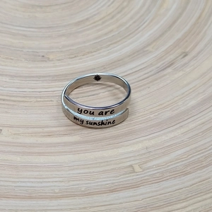 Adjustable stainless steel bypass ring with You Are My Sunshine engraving on wooden tray