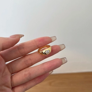 Close-up of a wide gold ring featuring a clear heart-shaped zircon worn on a hand
