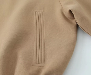 Détail de la veste décontractée kaki avec poche passepoilée et texture de tissu en sergé fin