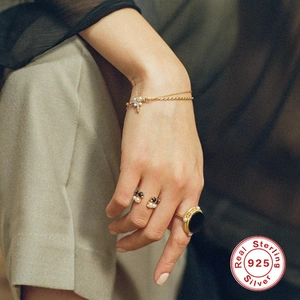 925 silver gold rings and pearl cross bracelet set worn on a female hand for daily wear