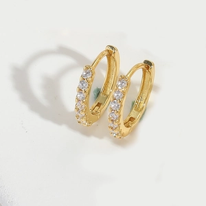 Close-up of elegant gold hoop earrings with sparkling diamond inlays on white background