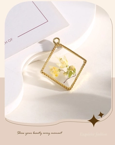 Detailed view of square gold-rimmed resin pendant with yellow dried flowers