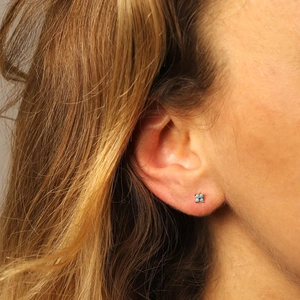 Close-up of a s925 silver four-leaf flower stud earring with turquoise blue cubic zirconia