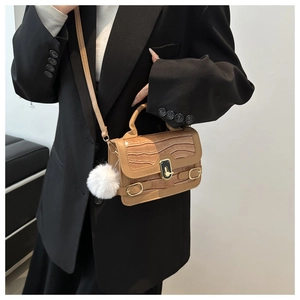 Detail der khakifarbenen Handtasche mit Kroko-Prägung, Goldschloss und Pelz-Anhänger