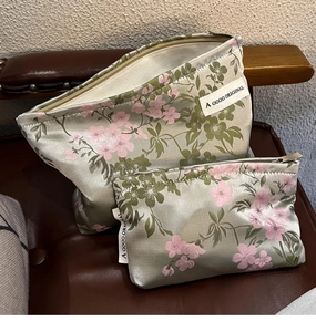 Detailed view of two green satin makeup bags with pink floral patterns on leather