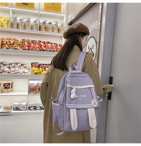 Detail of purple school backpack featuring cute white rabbit ears and matching plush pendant
