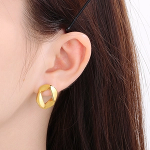 Close-up of 18K gold plated chunky 13mm Cuban link earrings worn on a model's ear