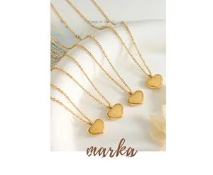 Detail of four golden heart pendant necklaces on a white ceramic plate over a magazine