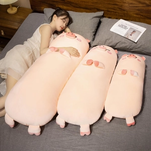 Three pink plush pig pillows in different sizes on a cozy bed with a sleeping model
