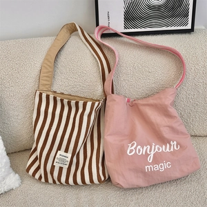 Dettaglio di grandi borse shopper in tela a righe con stampa Bonjour su divano
