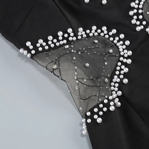 Close-up of pearl beadwork and sequin embroidery on black mesh fabric detail