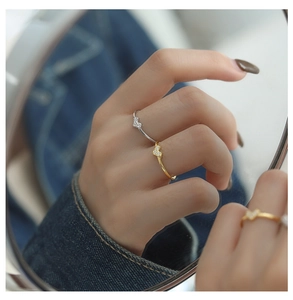 Macro shot of silver and gold V-shaped heart rings with zircon stones on denim background