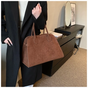 Brown faux suede tote bag with double handles and clean stitching detail in a lifestyle setting