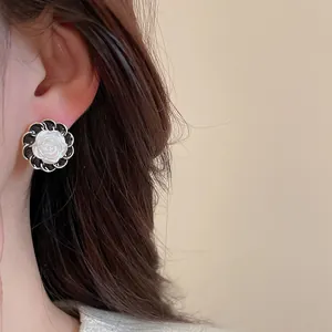 Dettaglio dell'orecchino vintage a fiore con rilievo a rosa bianca e bordo intrecciato
