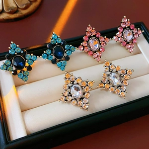 Dettaglio di tre paia di orecchini vintage a croce e stella con strass in una confezione