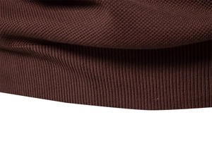 Makroaufnahme der dunkelbraunen Strickstruktur mit Rippbündchen am Herrenpullover