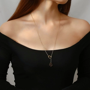 Detail of golden equestrian necklace featuring a horse head pendant and stirrup clasp on model