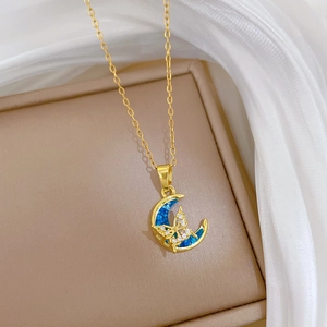 Close-up of gold moon and butterfly pendant with blue inlay and sparkling crystals