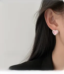 Close-up of pink heart-shaped earring with silver edges on a model's ear