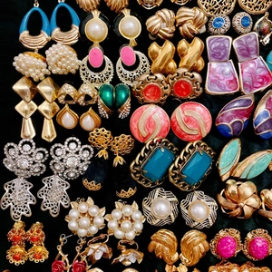 Collection of vintage luxury earrings in gold, enamel and pearls on black background