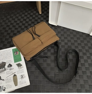 Detail of khaki nylon messenger bag with front utility pockets and outdoor cargo straps