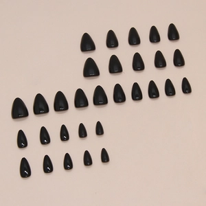 Glossy black short almond press-on nails set displayed on a minimalist beige background