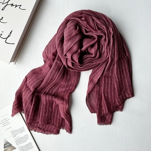 Elegant wine red pleated modal scarf with fringe ends on white wooden background