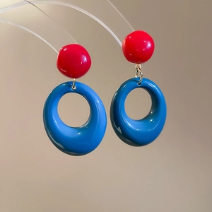 Vue détaillée des boucles d'oreilles pendantes en résine rouge et bleue polie