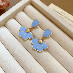 Macro detail of light blue enamel flower earrings with golden core in a jewelry box