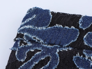 Detail of vintage hollow embroidery on black lace and blue denim patchwork pants