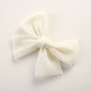 Close-up of a cream white mesh bow hair clip with delicate fabric texture for girls