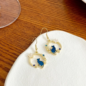 Detail of gold cat hoop earrings with blue rhinestones and dangling star crescent design
