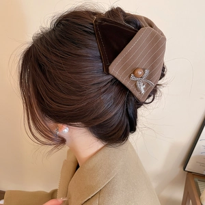 Detail einer braunen Haarklammer mit Karomuster, Samt und Vintage-Knopf am Hinterkopf