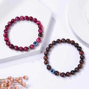 Nahaufnahme von 8mm Tigerauge-Perlen mit blauen Evil Eye Charms auf weißem Display