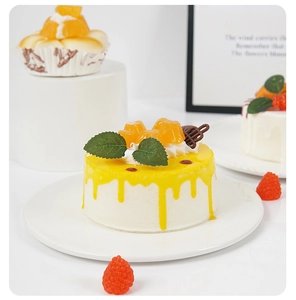 Detailed view of artificial mango mousse cake with mint leaf decoration on white plate