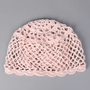 Détail du bonnet au crochet en tencel rose avec des vagues ajourées et des bords ondulés