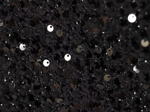 Macro detail of high-density black sequins on premium fabric showing luxury texture