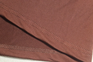 Detail shot of brown jersey fabric showing precise double-needle stitching and hem finish