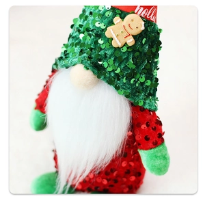 Dettaglio di un gnomo natalizio con cappello verde di paillettes e scritta holly
