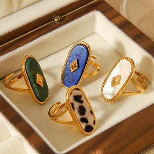 Detail view of oval natural stone rings in various colors displayed in a wooden box