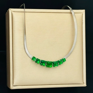 Detail of silver snake chain necklace featuring seven emerald green square-cut crystals