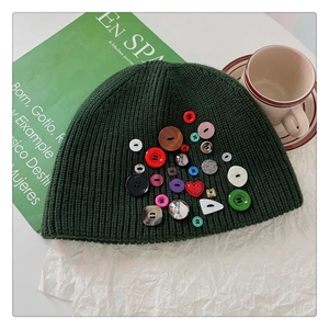 Close-up of dark green knitted beanie decorated with colorful mixed-shape novelty buttons