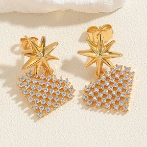 Macro detail of gold-plated star and heart-shaped stud earrings with zircon stones