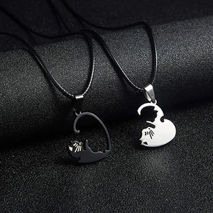 Close-up of black and silver cat pendants forming a heart on dark textured background